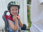 Happy boy with helmet on sitting in the rear of the cargo bike in a child seat