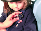 Close up of child in seat with hand adjusting the tightness of the seat belt harness.