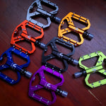 NEXT GEN ENZO ultra-light flat foot mountain bike pedals in titanium, orange, blue, gold, black, purple and green colours.